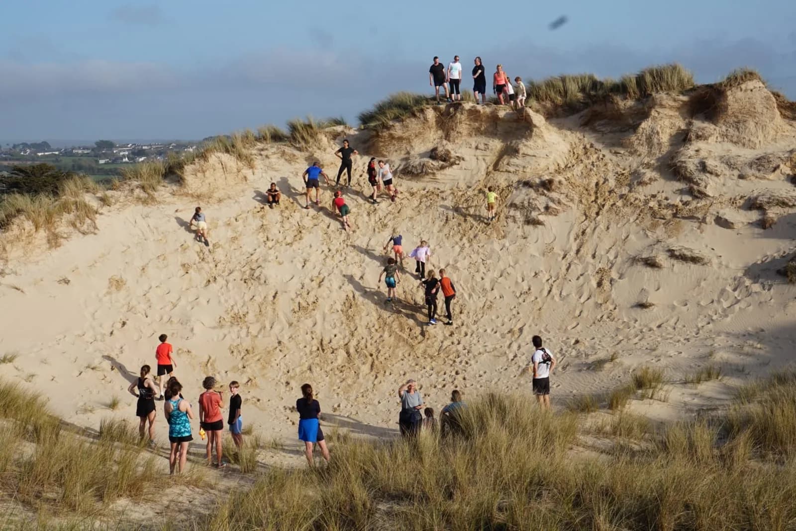 A wide dune bowl at Gwithian with a group spread out exploring it