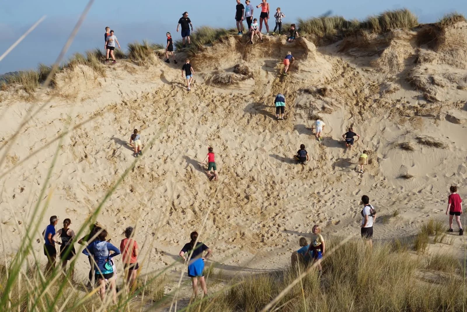 A group climbing a steep dune at Gwithian Towans
