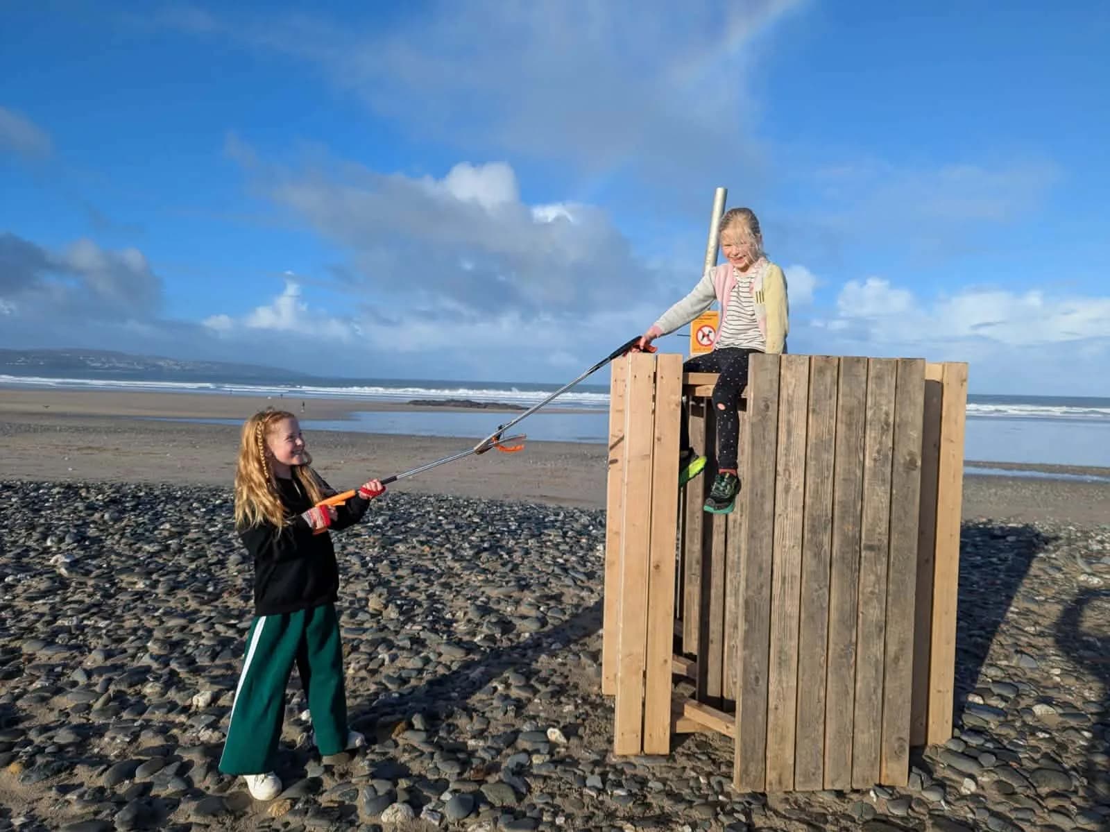 Children with litter grabbers picking up rubbish on the beach