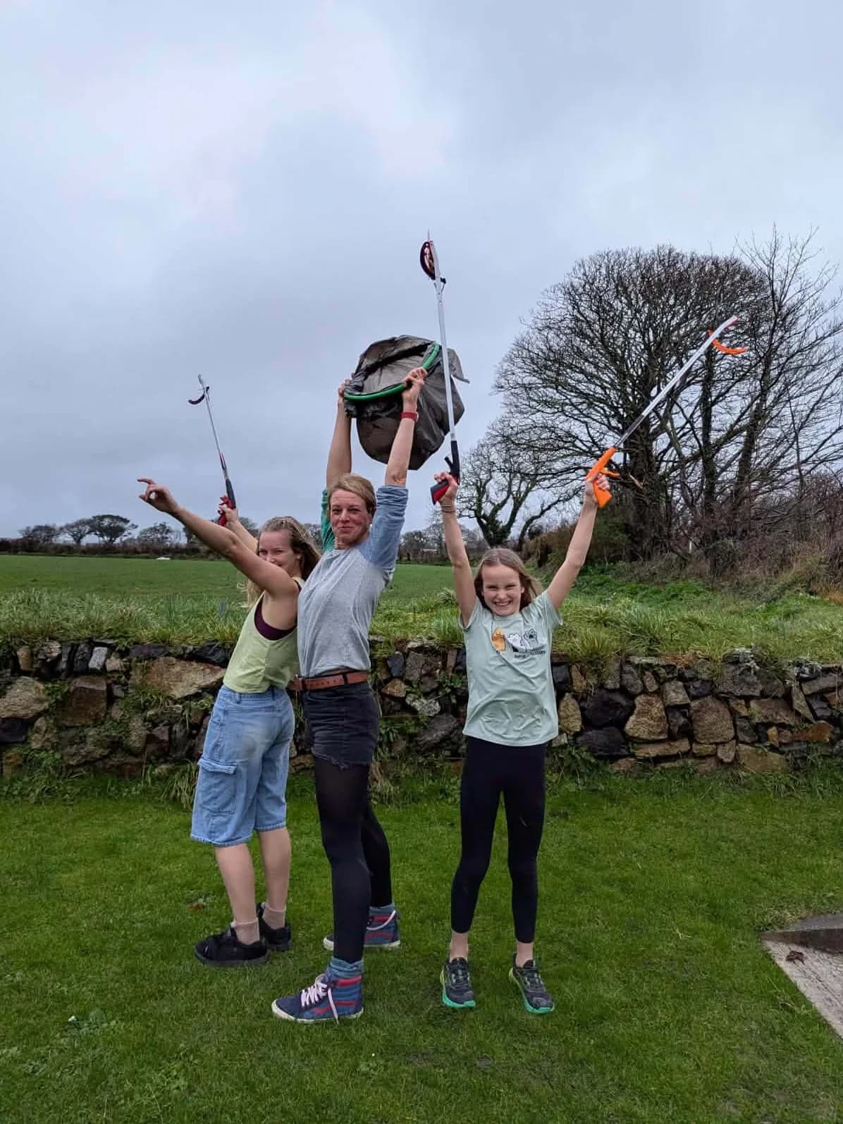 A litter-pick crew holding up a full bag in triumph
