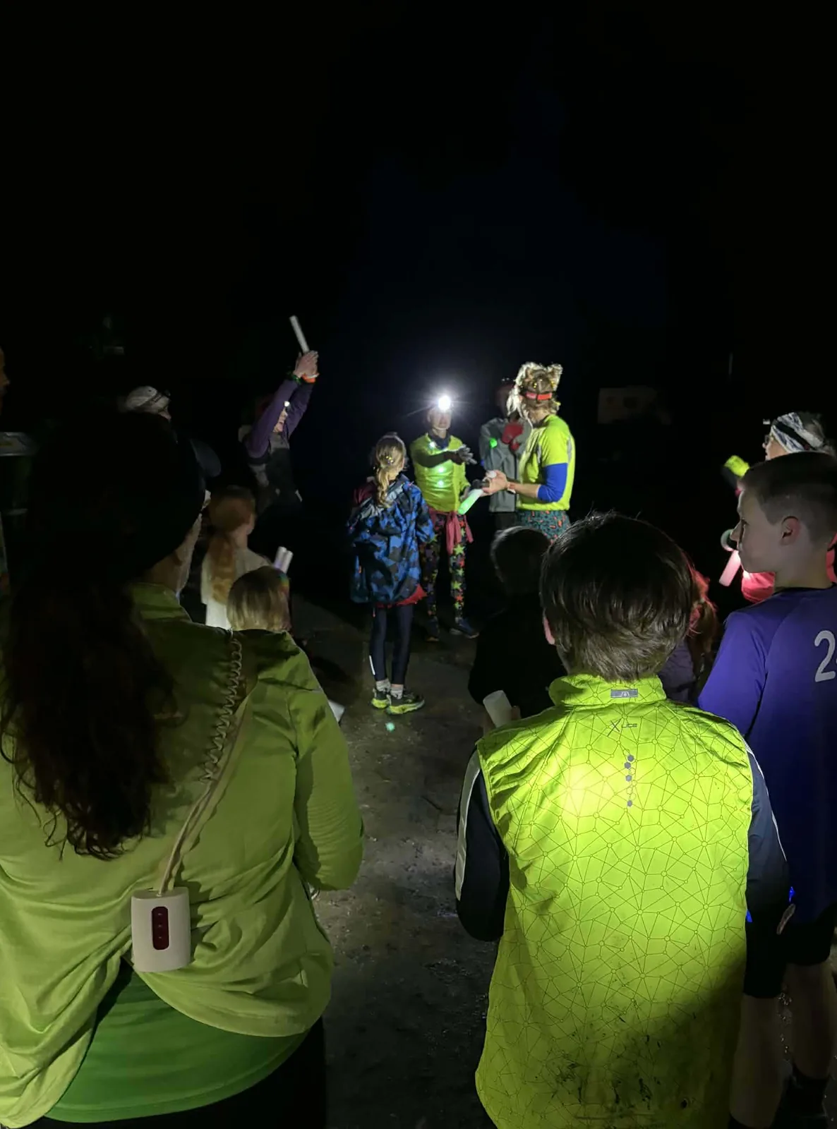 A huddle of runners with glow batons listening to the pre-run briefing