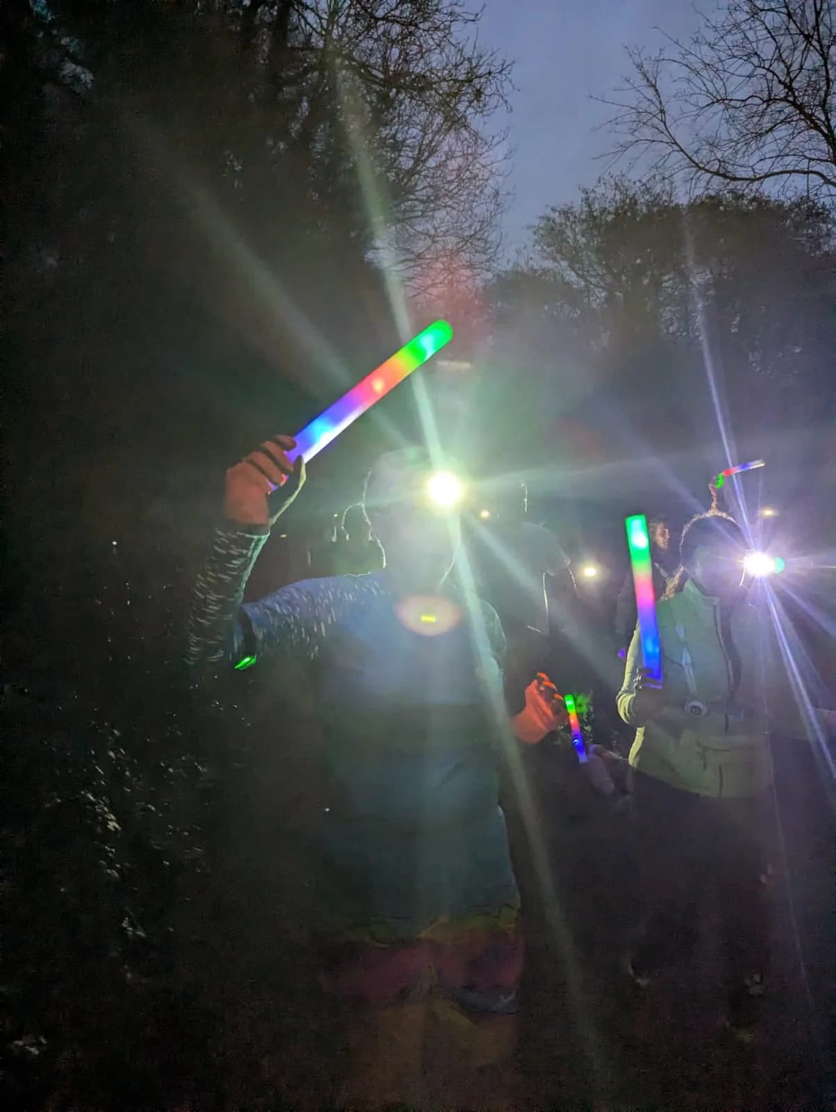 A child grinning with glow sticks at dusk