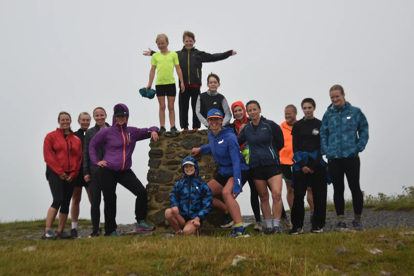 A group celebrating at a trig point summit