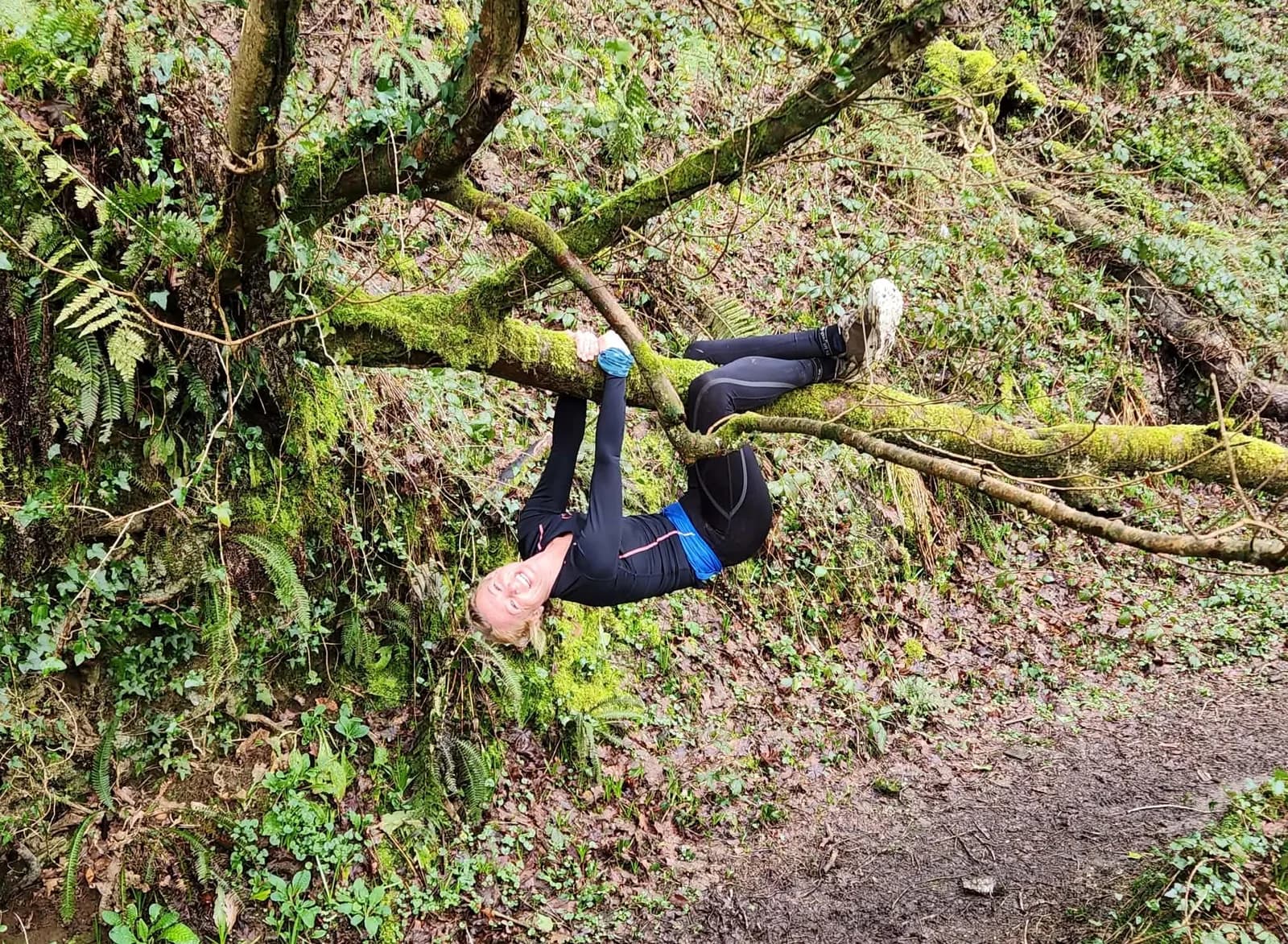 Ellie hanging upside-down from a tree branch, grinning